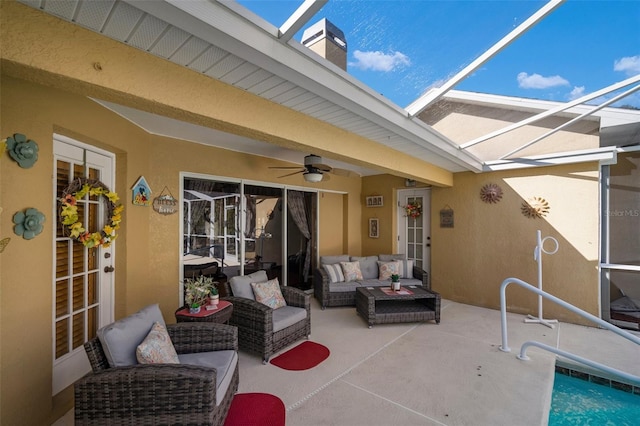 view of patio with ceiling fan, glass enclosure, and an outdoor living space