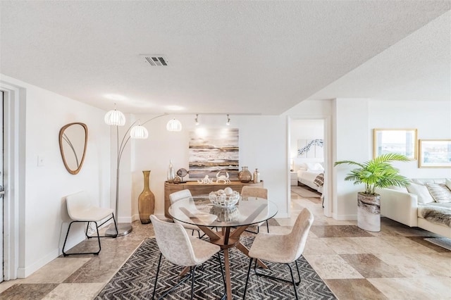 dining room with rail lighting and a textured ceiling