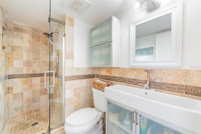 bathroom featuring tile walls, tasteful backsplash, toilet, a shower with shower door, and vanity