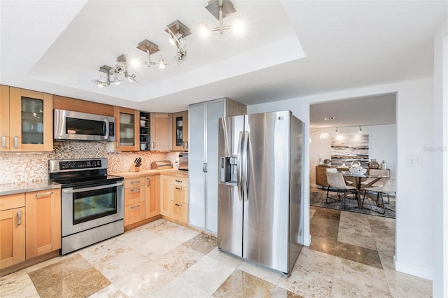 kitchen with stainless steel appliances, backsplash, and a tray ceiling