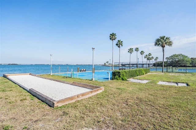 view of home's community with a lawn, a water view, and tennis court