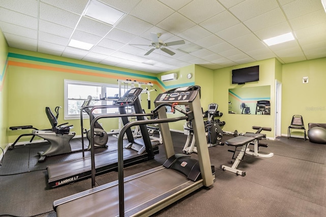 exercise room featuring ceiling fan, a paneled ceiling, and a wall unit AC