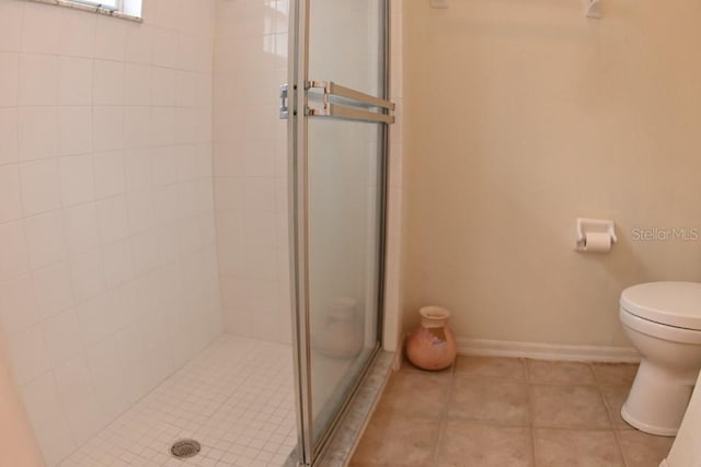 bathroom with baseboards, a stall shower, toilet, and tile patterned floors