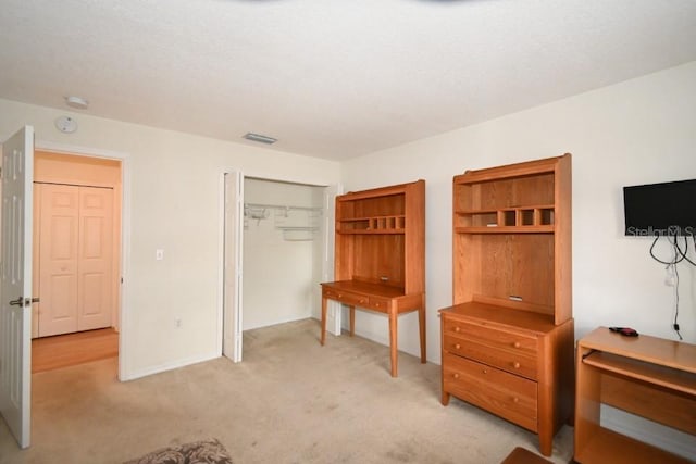 bedroom with visible vents, a closet, and light colored carpet