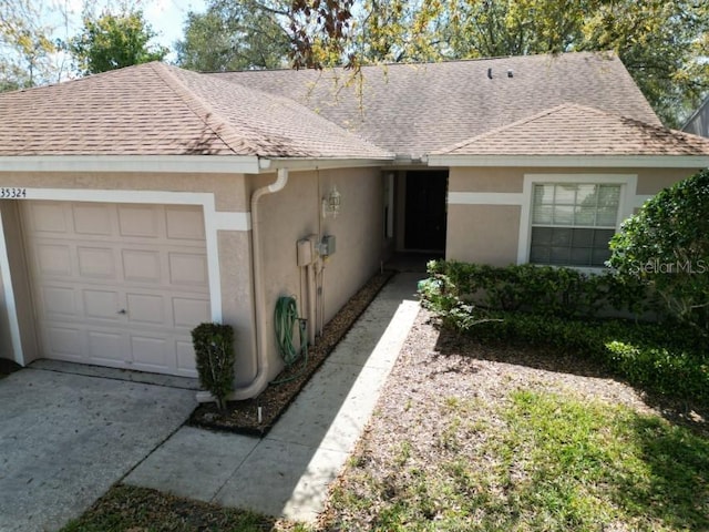 ranch-style home featuring driveway, a shingled roof, and stucco siding