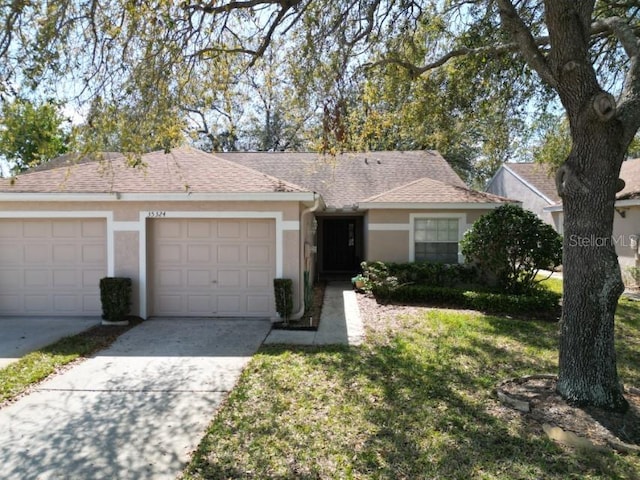 ranch-style home with a garage, driveway, stucco siding, roof with shingles, and a front yard