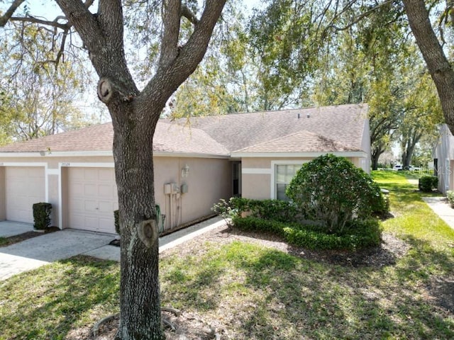 ranch-style home with an attached garage, a shingled roof, concrete driveway, and stucco siding