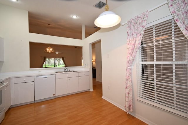 kitchen featuring white appliances, visible vents, light countertops, white cabinetry, and a sink