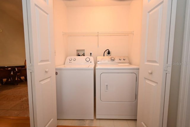 clothes washing area featuring light tile patterned floors, laundry area, and washing machine and clothes dryer