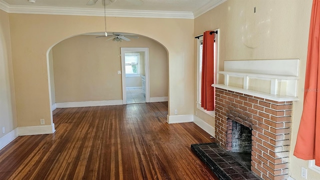 unfurnished living room with a fireplace, dark wood-type flooring, ornamental molding, and ceiling fan