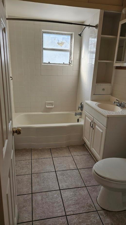 full bathroom with tiled shower / bath combo, vanity, tile patterned flooring, and toilet