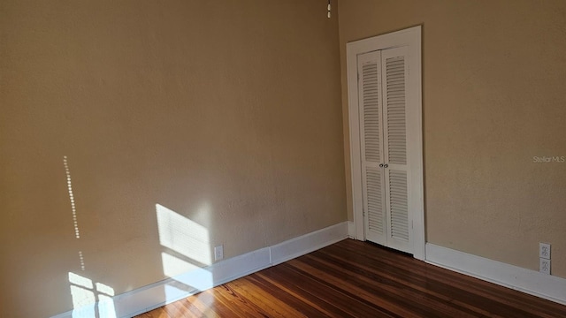 unfurnished bedroom featuring dark wood-type flooring and a closet