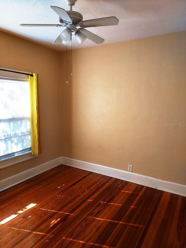 spare room with dark wood-type flooring and ceiling fan