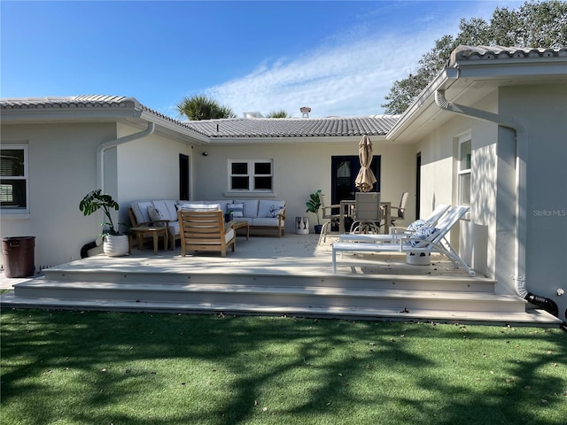 back of house featuring an outdoor living space, a wooden deck, and a lawn