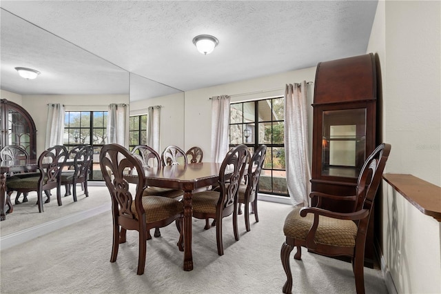 dining area featuring light colored carpet and a textured ceiling