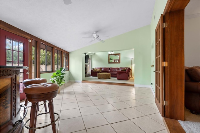 tiled living room with ceiling fan and lofted ceiling