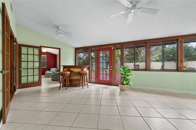 sunroom / solarium with lofted ceiling, ceiling fan, plenty of natural light, and french doors