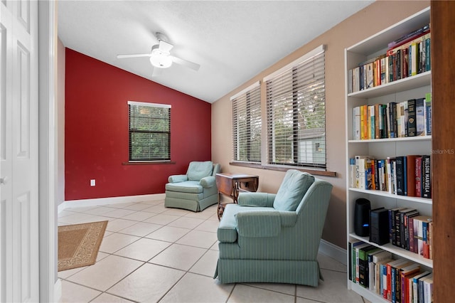 living area with vaulted ceiling, ceiling fan, light tile patterned floors, and a healthy amount of sunlight