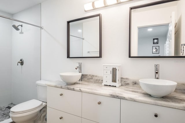 bathroom featuring toilet, vanity, and a tile shower