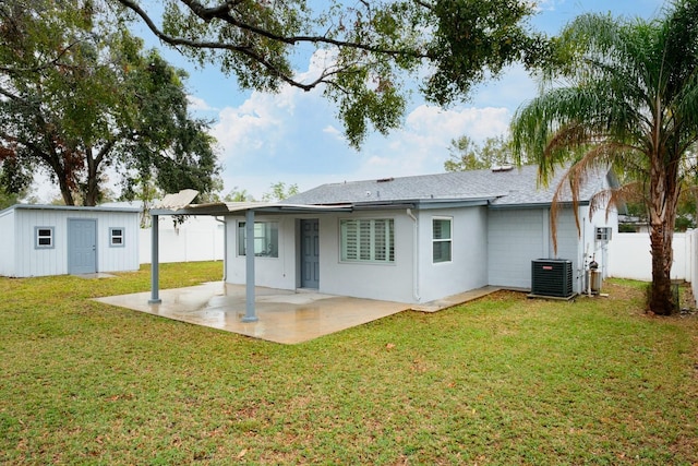 rear view of house with a lawn, an outbuilding, central air condition unit, and a patio