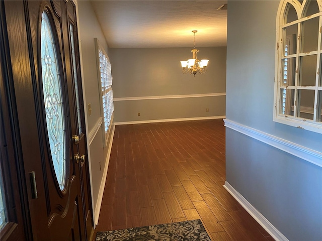 foyer entrance with baseboards, a chandelier, and dark wood finished floors