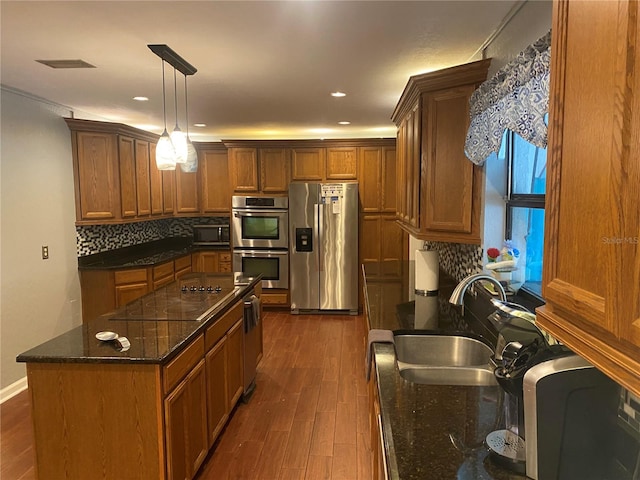 kitchen featuring dark wood-style flooring, backsplash, appliances with stainless steel finishes, brown cabinetry, and a sink