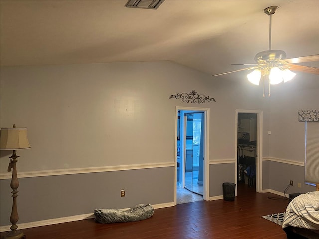 bedroom with wood finished floors, visible vents, baseboards, vaulted ceiling, and ensuite bath