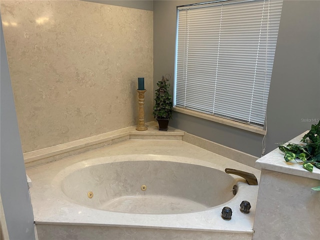 bathroom with a textured wall and a jetted tub