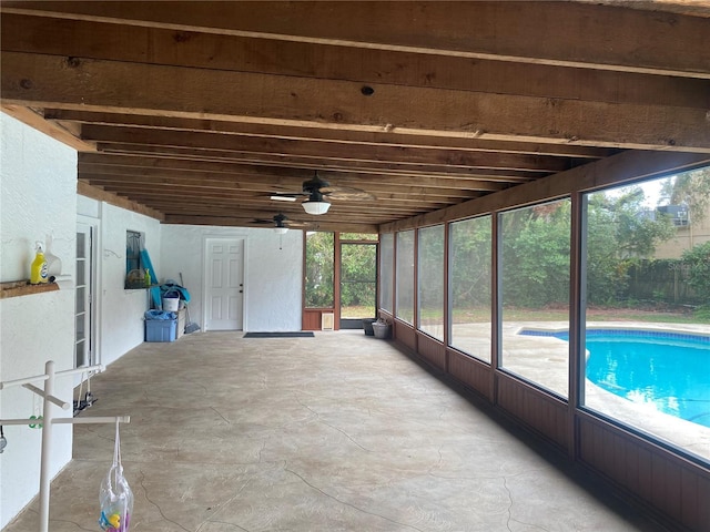 unfurnished sunroom with a ceiling fan and beam ceiling