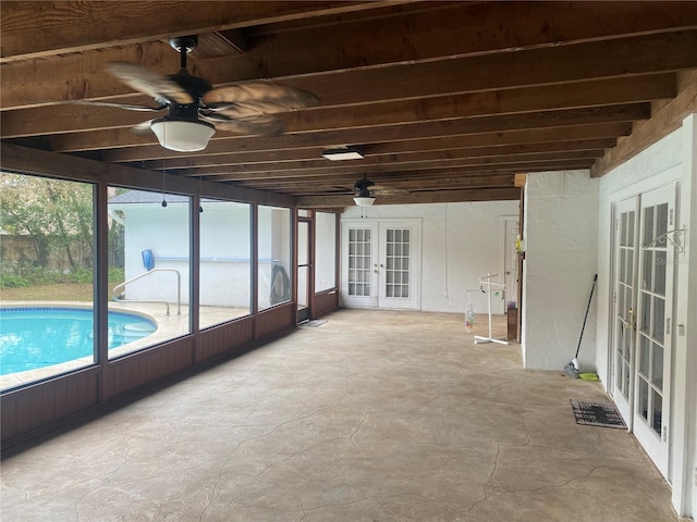 unfurnished sunroom with a ceiling fan and french doors