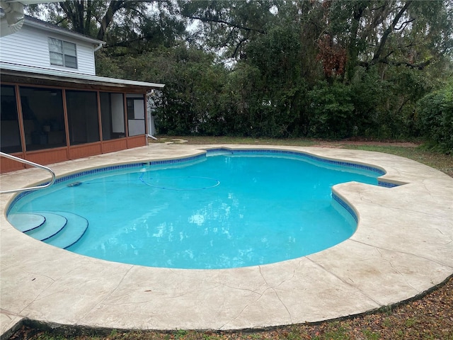 outdoor pool with a sunroom and a patio