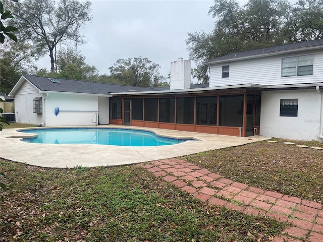 back of house with an outdoor pool, a sunroom, a chimney, a patio area, and stucco siding