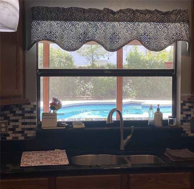 kitchen featuring dark countertops, tasteful backsplash, and a sink