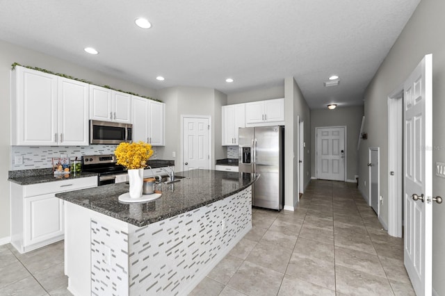 kitchen with white cabinets, stainless steel appliances, and an island with sink