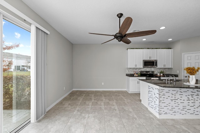 kitchen with white cabinetry, decorative backsplash, sink, dark stone countertops, and stainless steel appliances