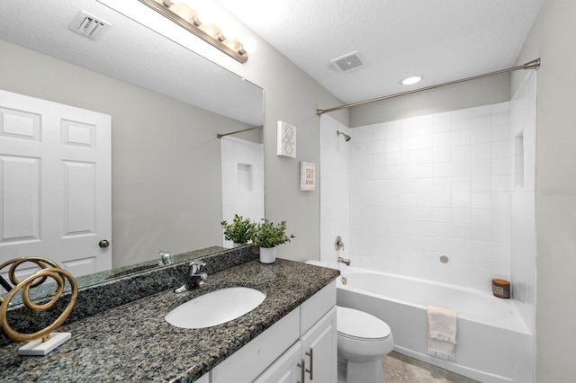 full bathroom featuring a textured ceiling, tiled shower / bath combo, vanity, and toilet