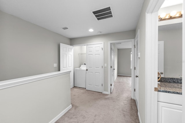 hall featuring washer / clothes dryer and light carpet