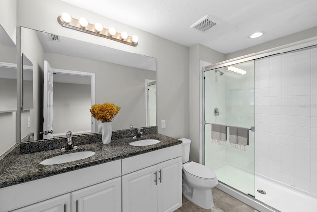 bathroom featuring vanity, toilet, a textured ceiling, and a shower with door