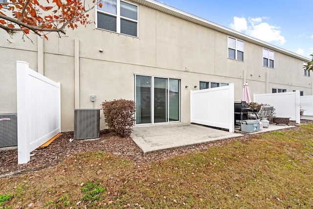 rear view of house featuring central air condition unit, a patio area, and a lawn