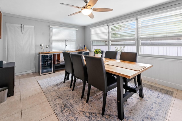 dining area featuring ceiling fan, light tile patterned floors, beverage cooler, and crown molding