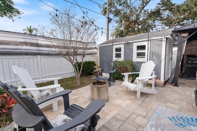 view of patio / terrace featuring an outdoor fire pit, a grill, and a storage shed