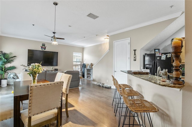 dining area with ceiling fan, a textured ceiling, light hardwood / wood-style flooring, and ornamental molding