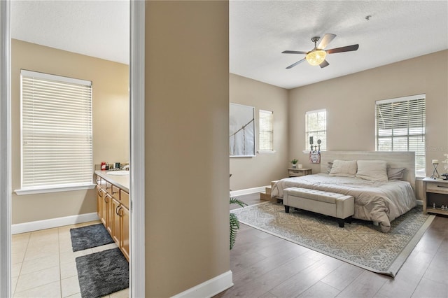 bedroom with ceiling fan, a textured ceiling, and light hardwood / wood-style flooring