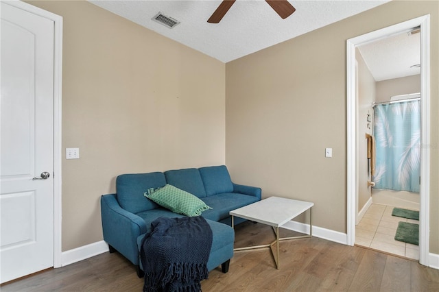 sitting room with ceiling fan, a textured ceiling, and wood-type flooring