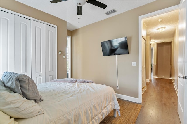 bedroom with ceiling fan, a textured ceiling, a closet, and light wood-type flooring