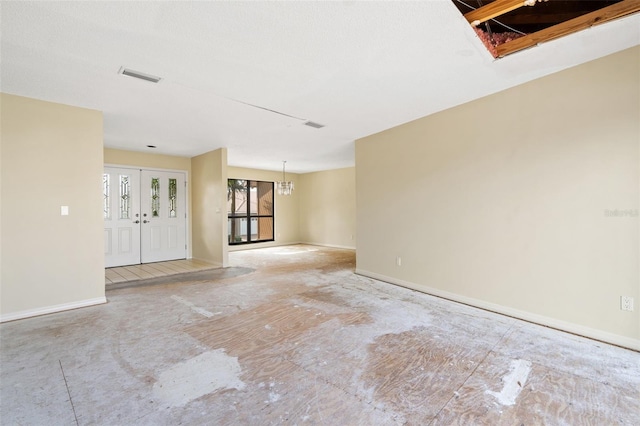 unfurnished room featuring a chandelier and french doors