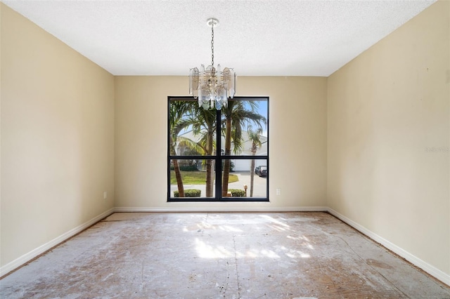 spare room featuring a textured ceiling and a notable chandelier