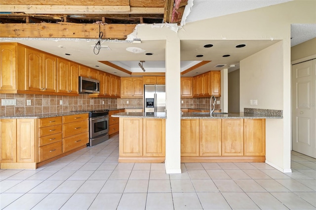 kitchen with light tile patterned floors, kitchen peninsula, appliances with stainless steel finishes, a tray ceiling, and stone countertops