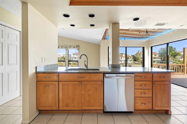 kitchen with sink, light tile patterned floors, dishwasher, and vaulted ceiling