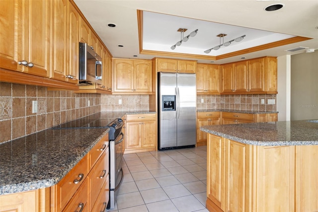 kitchen featuring light tile patterned flooring, stainless steel appliances, backsplash, and a raised ceiling